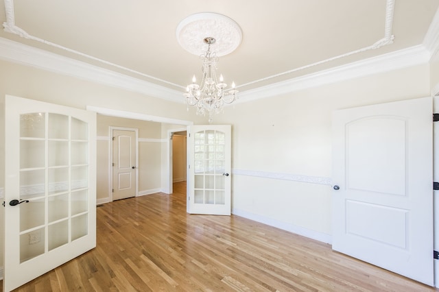 unfurnished room with an inviting chandelier, french doors, hardwood / wood-style flooring, and ornamental molding