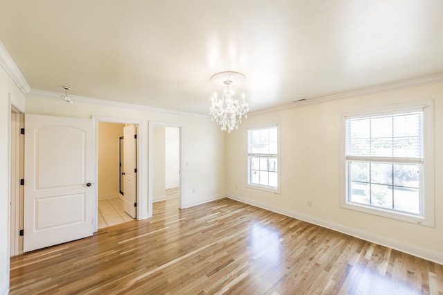 spare room featuring light wood-type flooring, an inviting chandelier, and ornamental molding