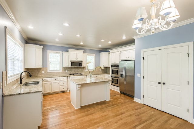 kitchen with stainless steel appliances, light hardwood / wood-style floors, sink, hanging light fixtures, and a kitchen island