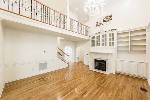 unfurnished living room with a high ceiling, light hardwood / wood-style flooring, and ornamental molding