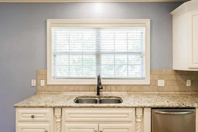 kitchen with dishwasher, decorative backsplash, sink, and light stone counters