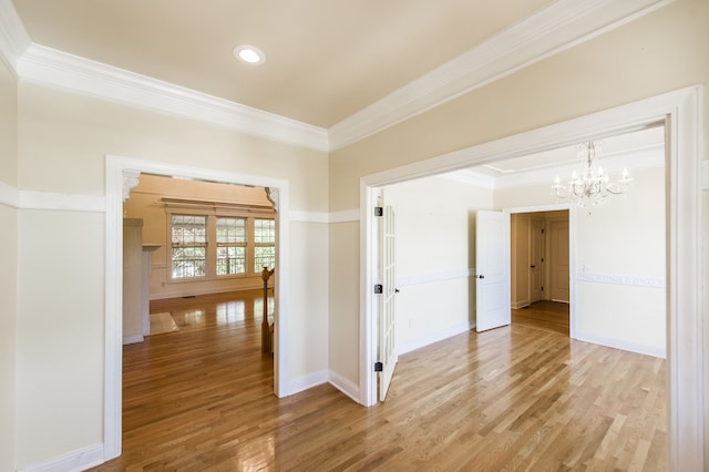 spare room with ornamental molding, wood-type flooring, and a chandelier