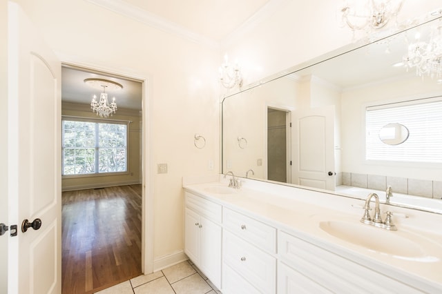 bathroom with wood-type flooring, crown molding, vanity, a notable chandelier, and a washtub