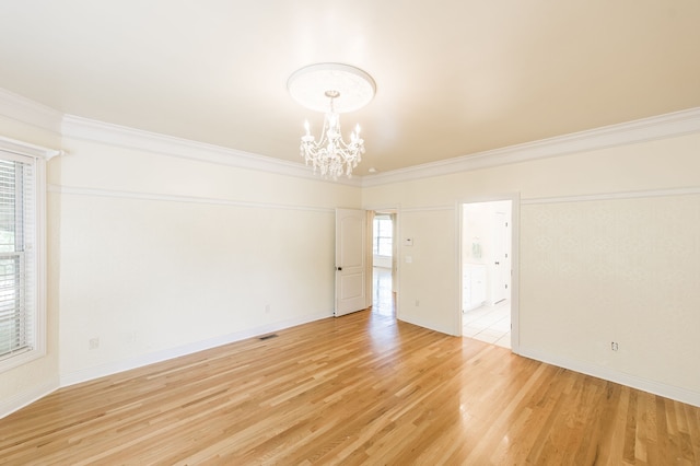 unfurnished room featuring an inviting chandelier, wood-type flooring, crown molding, and plenty of natural light