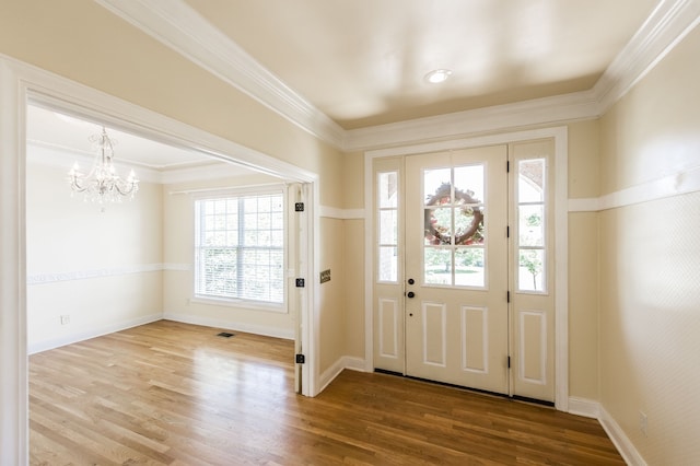 foyer featuring a notable chandelier, hardwood / wood-style flooring, and crown molding