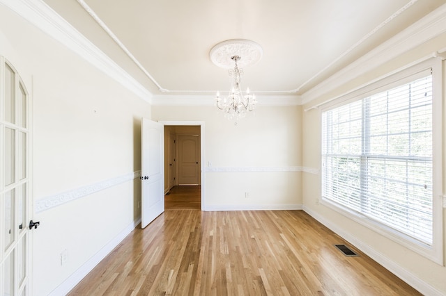 spare room featuring ornamental molding, an inviting chandelier, and light hardwood / wood-style floors