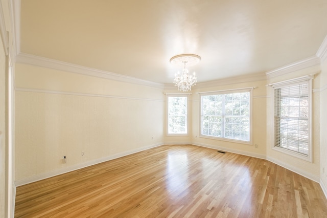 spare room featuring a wealth of natural light, a chandelier, light hardwood / wood-style flooring, and ornamental molding