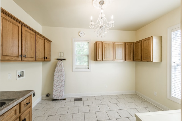 clothes washing area with cabinets, light tile patterned floors, hookup for a washing machine, and an inviting chandelier