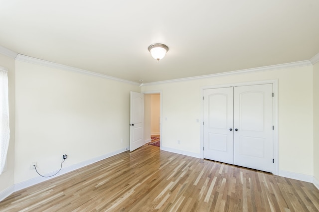 unfurnished bedroom featuring light hardwood / wood-style floors, crown molding, and a closet