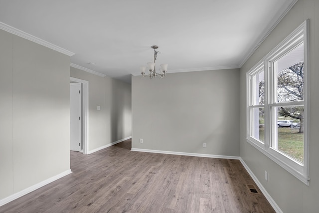 spare room with hardwood / wood-style floors, an inviting chandelier, and crown molding