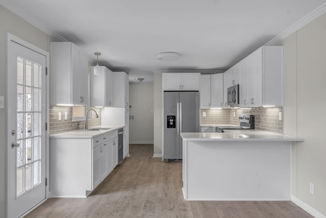 kitchen with stainless steel appliances, white cabinets, sink, backsplash, and pendant lighting