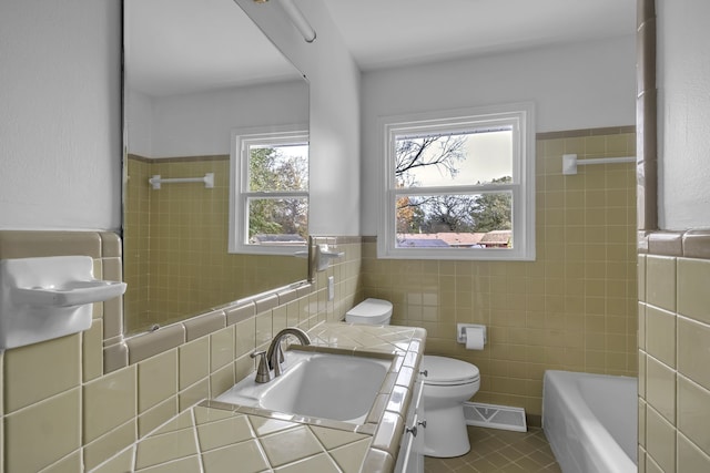 bathroom with tile walls, tile patterned flooring, vanity, and a bath