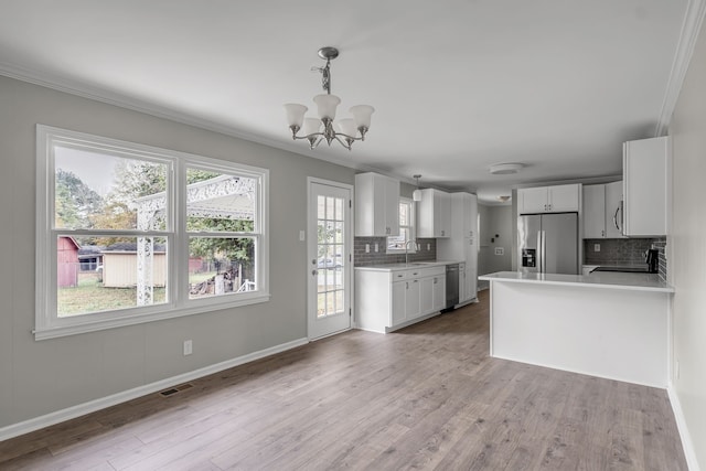 kitchen featuring decorative backsplash, hanging light fixtures, sink, white cabinetry, and appliances with stainless steel finishes