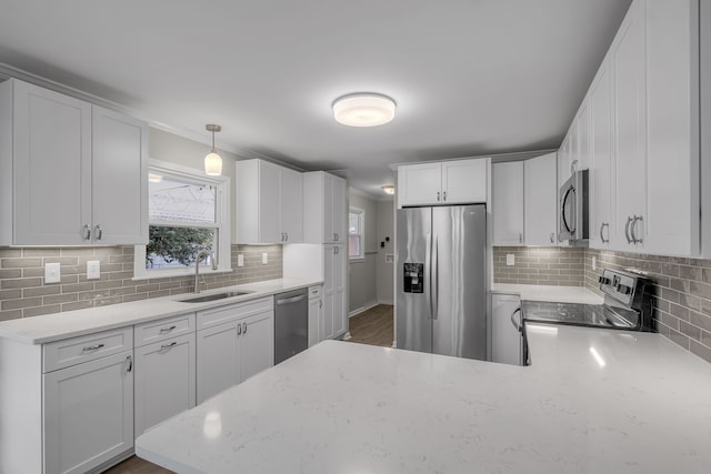 kitchen featuring white cabinets, stainless steel appliances, tasteful backsplash, and decorative light fixtures