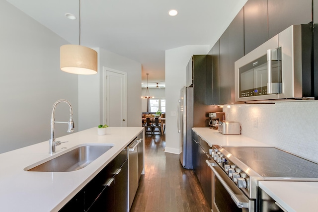 kitchen featuring stainless steel appliances, dark wood-type flooring, hanging light fixtures, sink, and backsplash