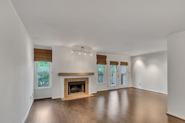 unfurnished living room with a brick fireplace, hardwood / wood-style flooring, and crown molding