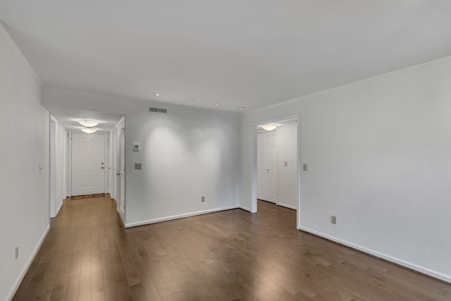 spare room featuring dark wood-type flooring and crown molding