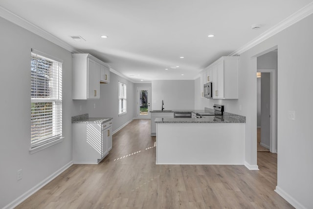 kitchen with stainless steel appliances, light stone countertops, and white cabinets