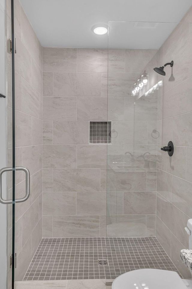 bathroom with a shower with shower door and toilet