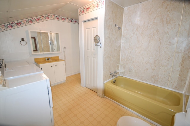 bathroom featuring vanity, washer and clothes dryer, tub / shower combination, and vaulted ceiling