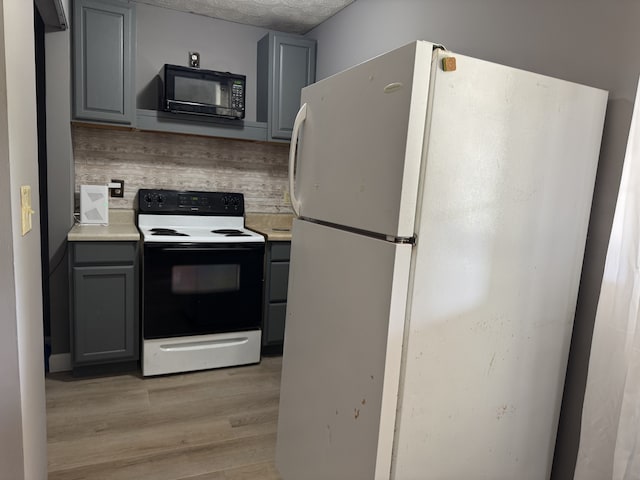 kitchen with light hardwood / wood-style flooring, white appliances, gray cabinetry, and backsplash