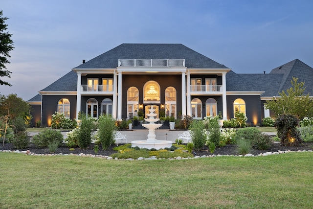 view of front of property featuring a balcony and a yard