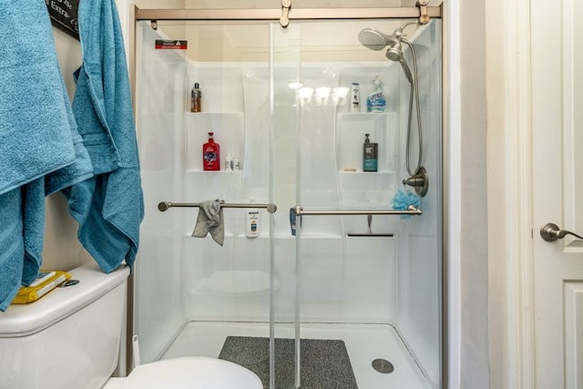 bathroom with a shower with door and toilet