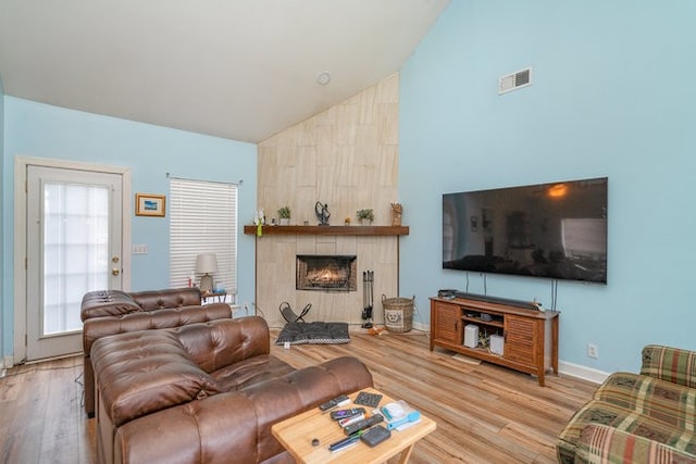 living room with hardwood / wood-style flooring, a large fireplace, and high vaulted ceiling