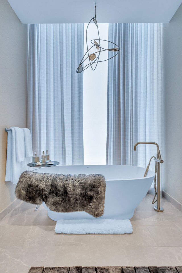 bathroom with a notable chandelier and a tub