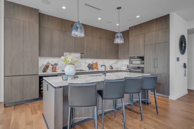 kitchen featuring hanging light fixtures, sink, a large island with sink, and a breakfast bar