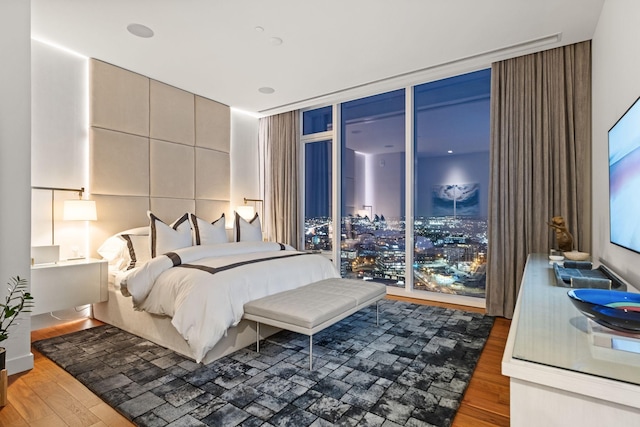 bedroom with floor to ceiling windows and wood-type flooring