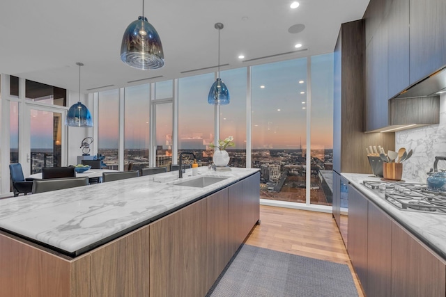 kitchen featuring expansive windows, sink, light hardwood / wood-style flooring, and decorative light fixtures