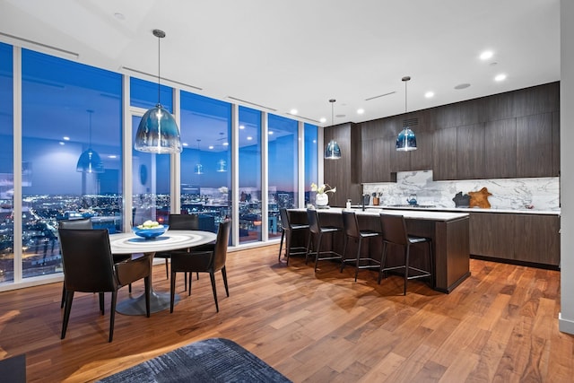 kitchen featuring pendant lighting, light hardwood / wood-style flooring, expansive windows, and a center island with sink