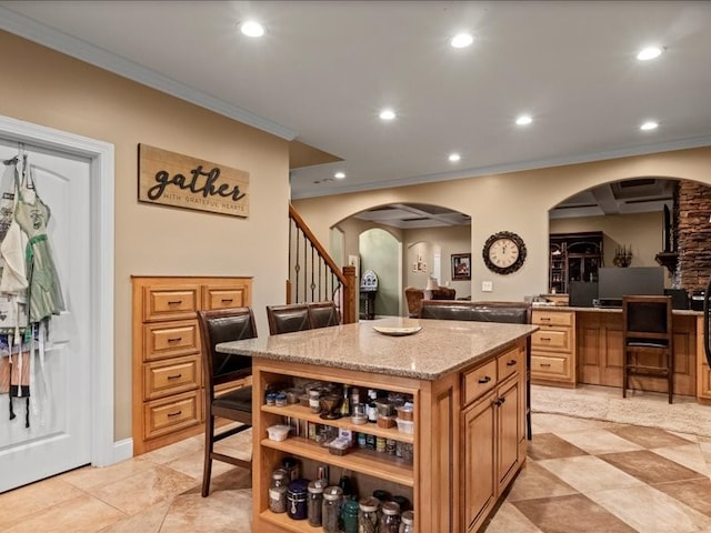 kitchen with light stone counters, a kitchen island, and ornamental molding