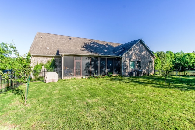 rear view of property with a lawn and a sunroom