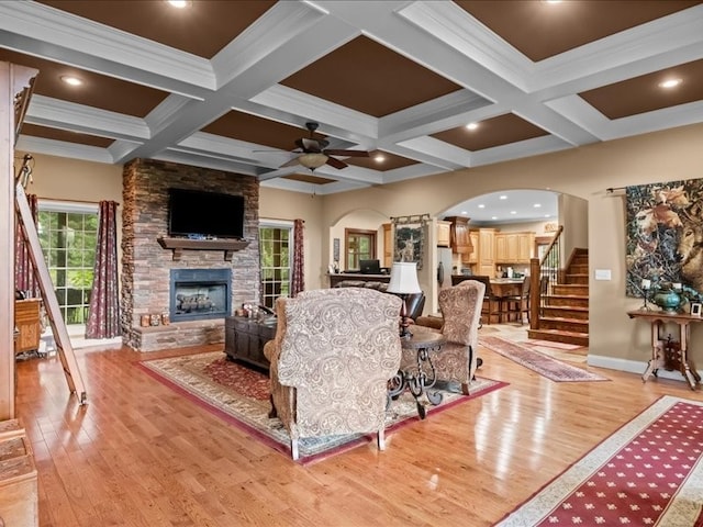 living room featuring a fireplace, coffered ceiling, beam ceiling, and light hardwood / wood-style flooring