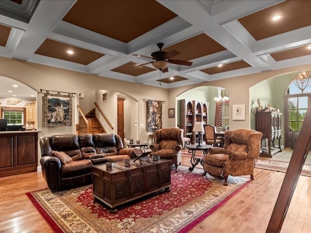 living room with coffered ceiling, ceiling fan with notable chandelier, light hardwood / wood-style floors, and beam ceiling