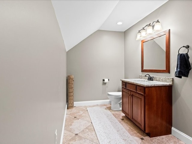 bathroom featuring toilet, vanity, and lofted ceiling