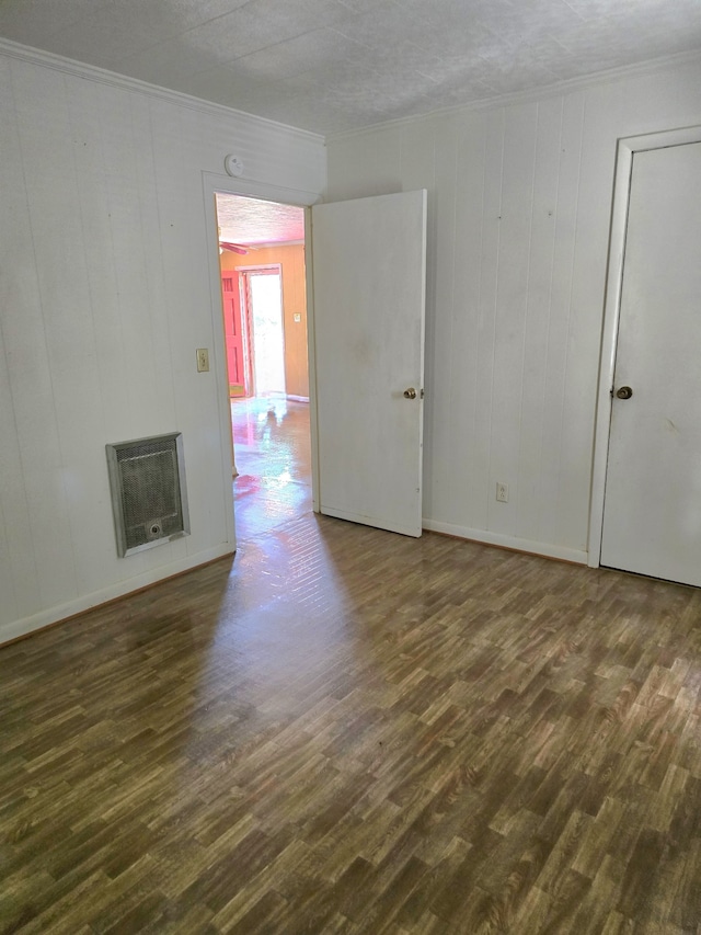 unfurnished room with crown molding, dark hardwood / wood-style floors, heating unit, and a textured ceiling