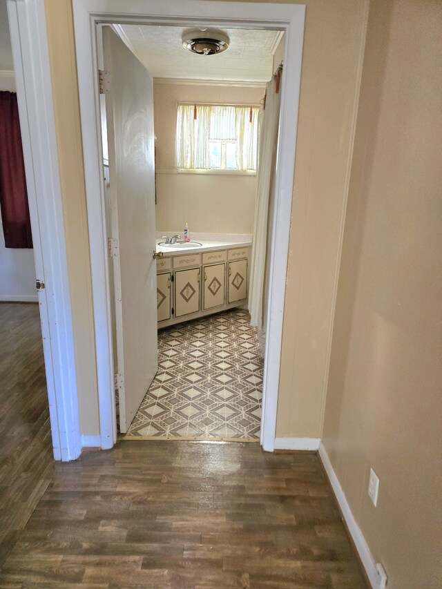 corridor featuring crown molding, sink, and hardwood / wood-style flooring