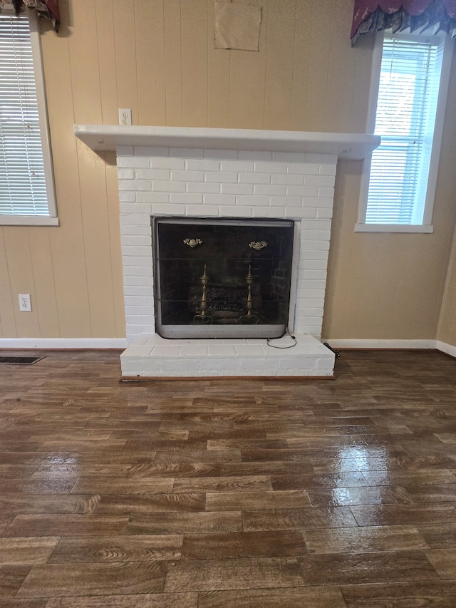 interior details featuring hardwood / wood-style flooring, a brick fireplace, and wood walls