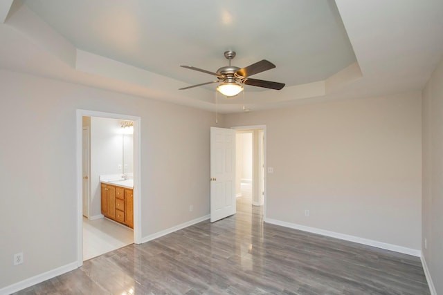 spare room featuring a raised ceiling, ceiling fan, and hardwood / wood-style flooring