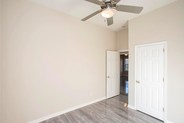 unfurnished bedroom featuring ceiling fan, light wood-type flooring, and a high ceiling