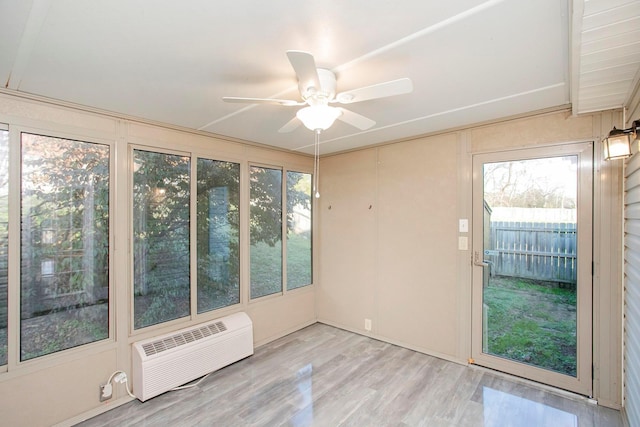 unfurnished sunroom with an AC wall unit and ceiling fan