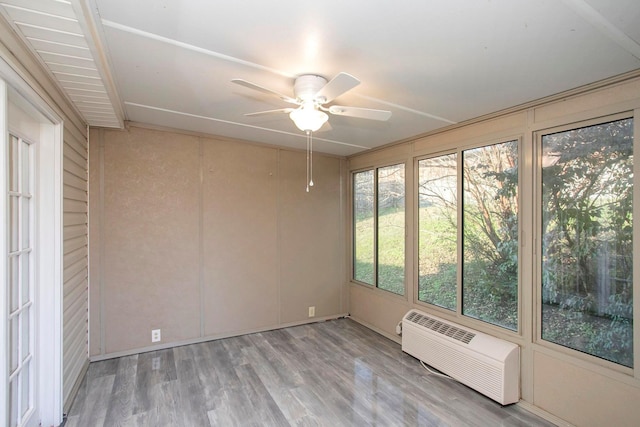 unfurnished sunroom featuring an AC wall unit and ceiling fan