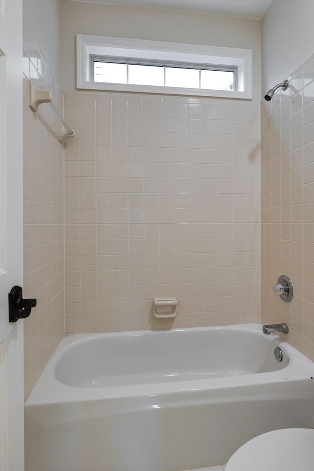 bathroom featuring tiled shower / bath combo and toilet