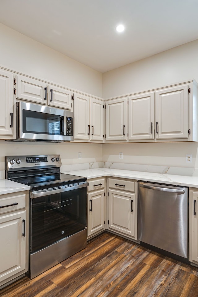 kitchen with stainless steel appliances, dark hardwood / wood-style floors, white cabinetry, and light stone counters