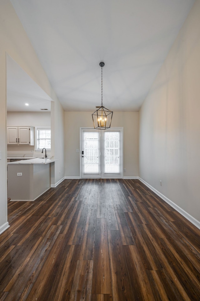 unfurnished dining area featuring an inviting chandelier, sink, and dark hardwood / wood-style floors