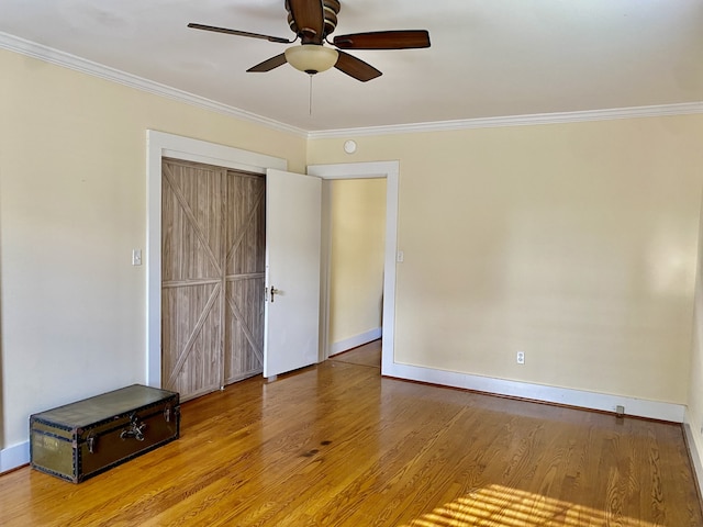 empty room with ceiling fan, wood-type flooring, and crown molding