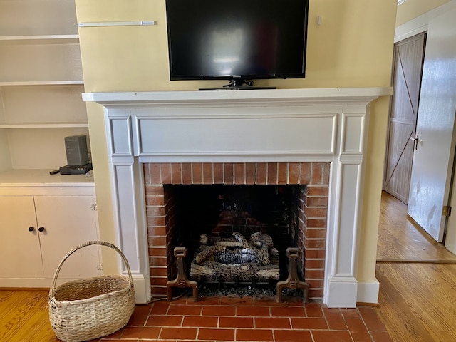 interior details with a brick fireplace and wood-type flooring